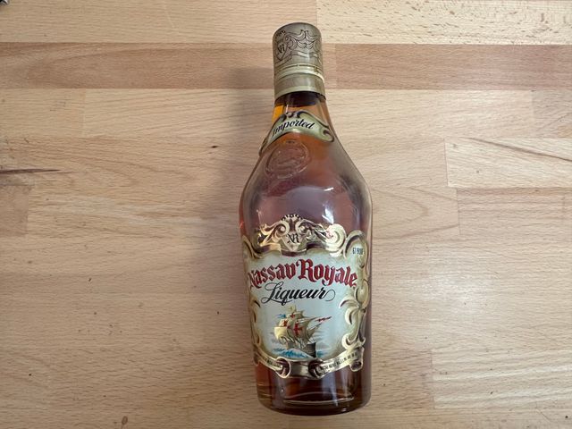 A dusty looking bottle of Nassau Royale on a wooden table.