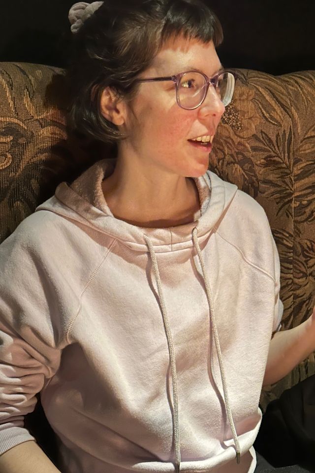 Close up portrait of the same woman, but this image is crisper and brighter, though it has a visible graininess. Even the texture of the upholstery of her seat shows better.